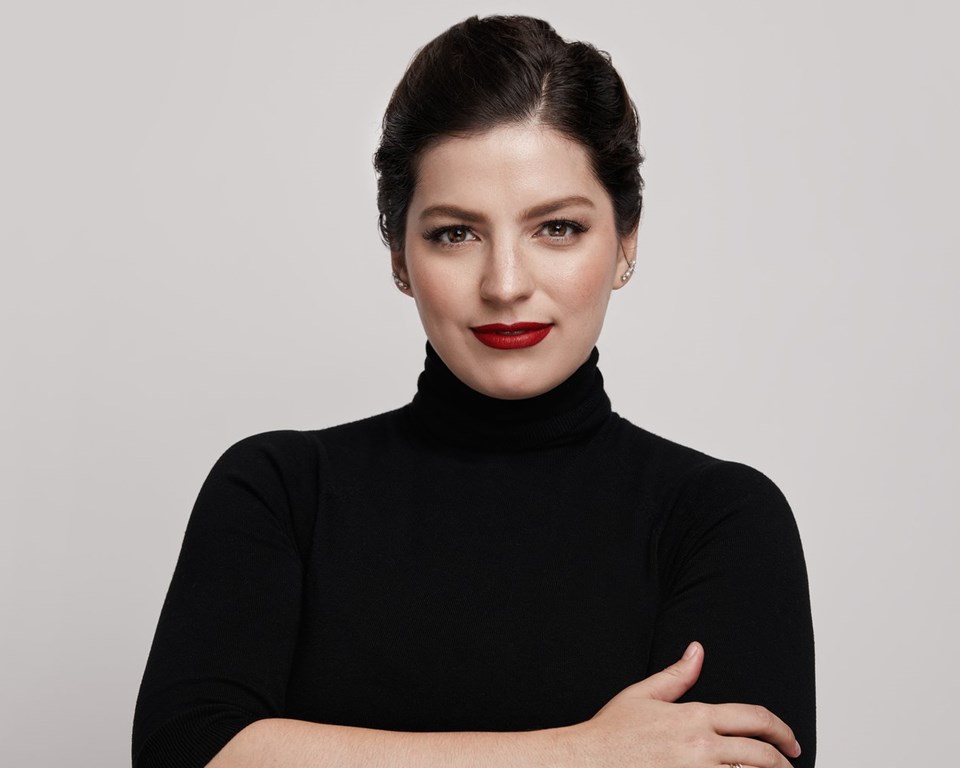 Women with brown hair and black turtleneck looking at camera