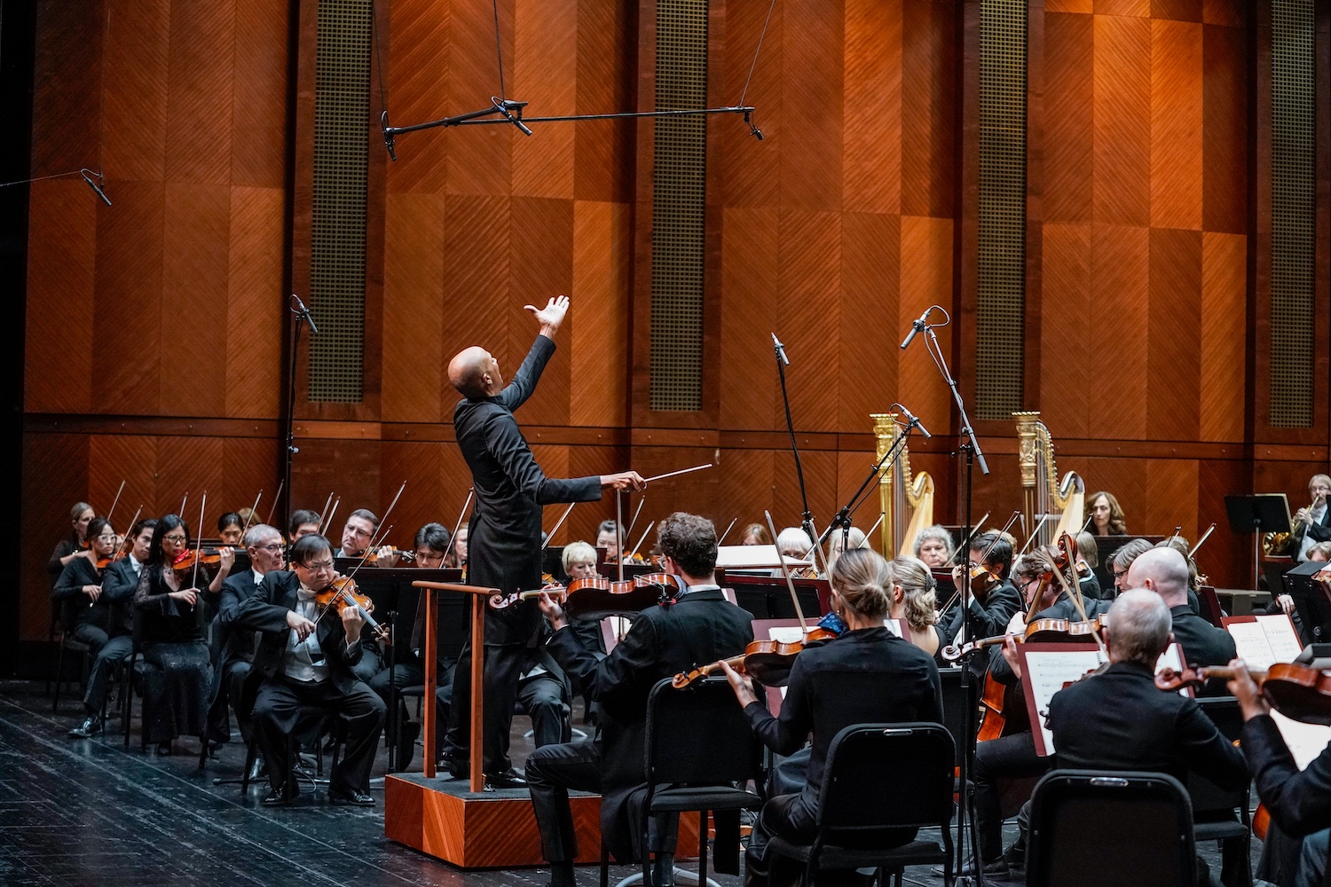 black conductor with arm raised high above orchestra
