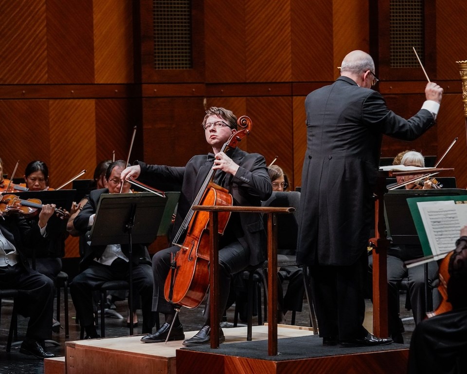 White man with medium length hair playing cello solo