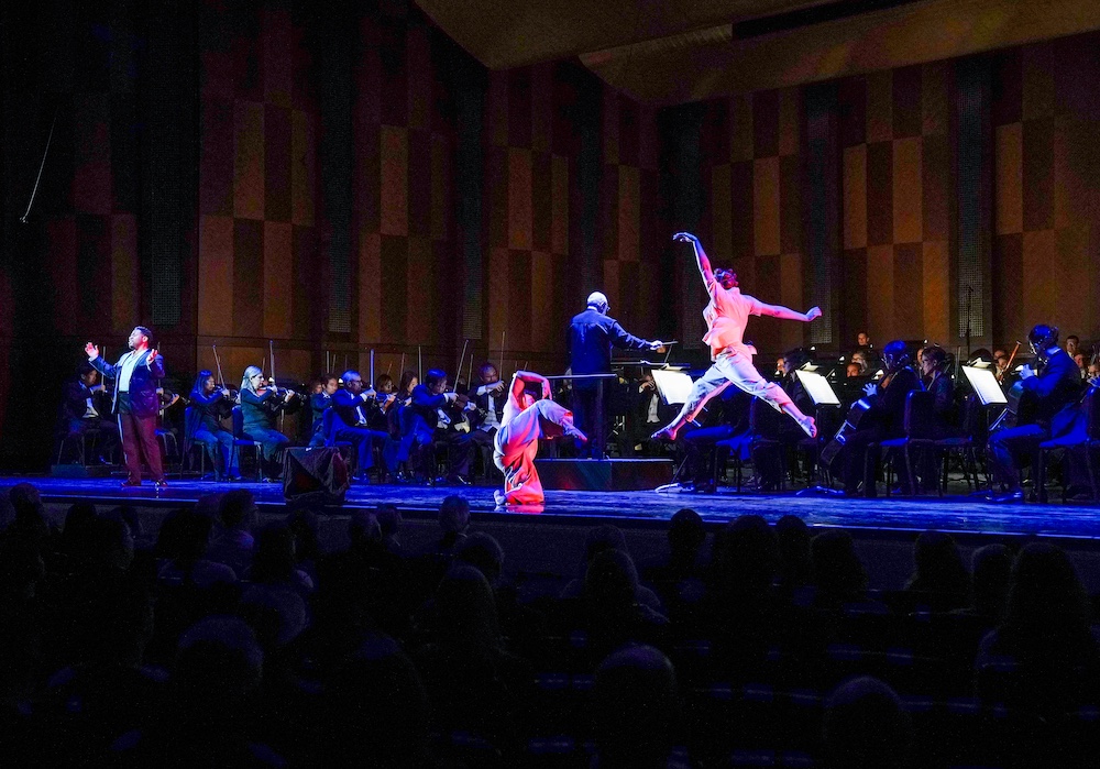 Two black female dancers sharing the stage with an orchestra and black male soloist