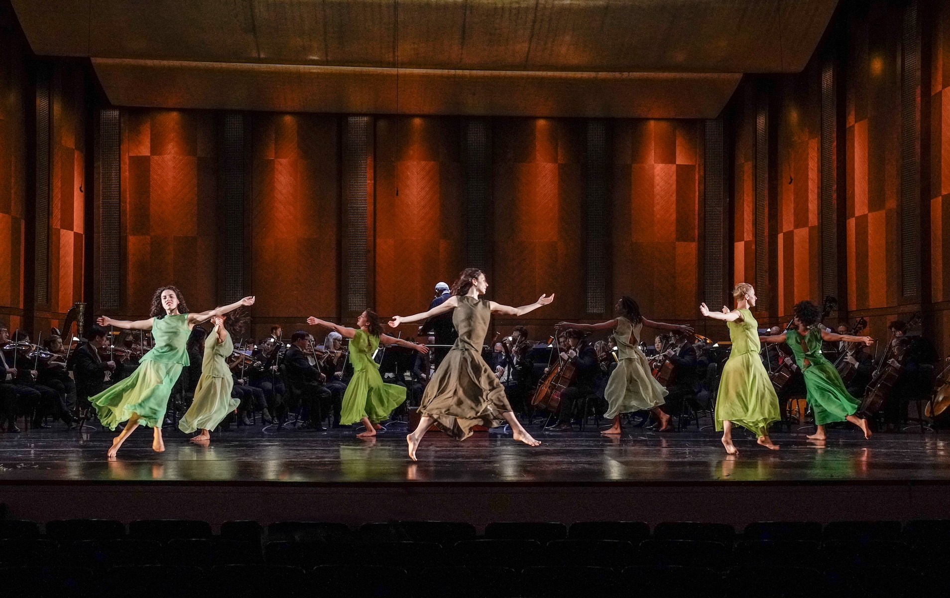 women in flowy green dresses dancing in a circular formation