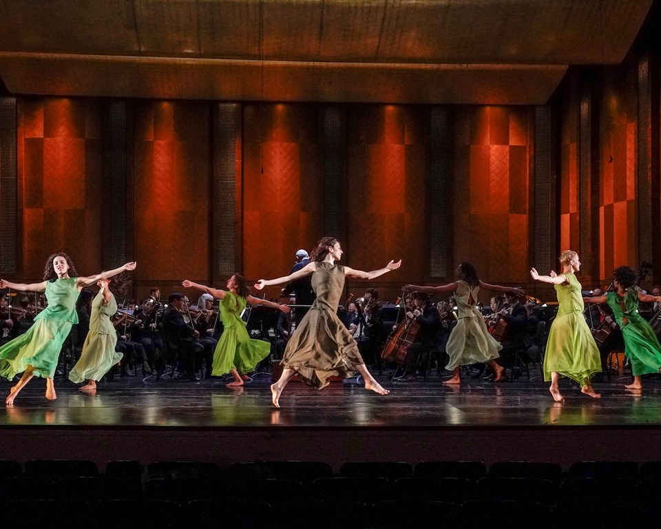 women in flowy green dresses dancing in a circular formation