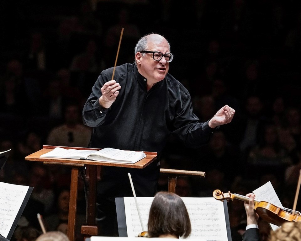 conductor in all black dress with glasses during concert