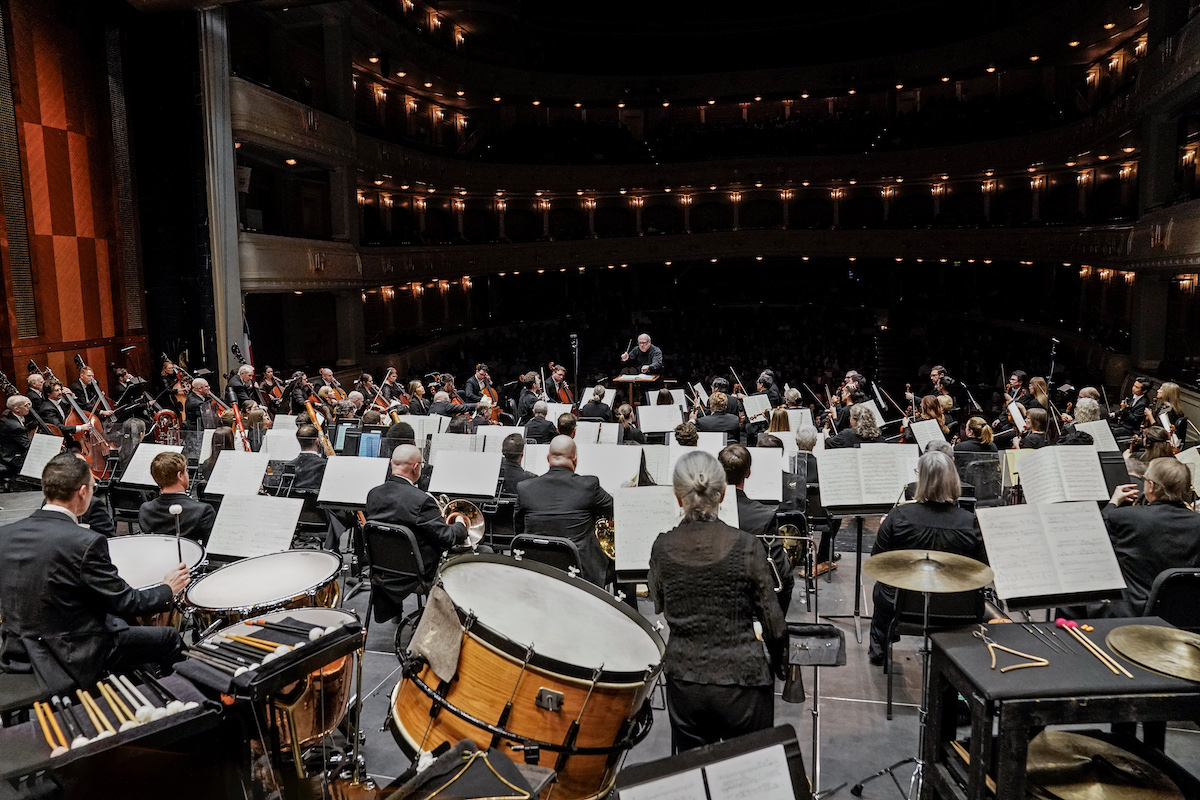 Conductor conducting symphony orchestra in performance hall