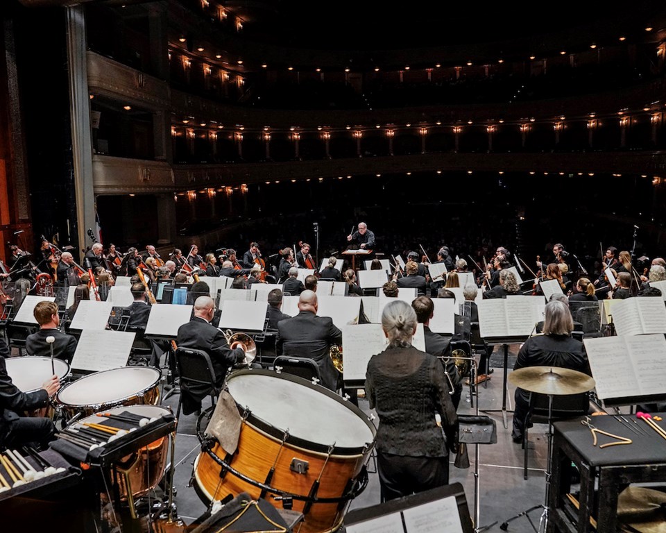 Conductor conducting symphony orchestra in performance hall