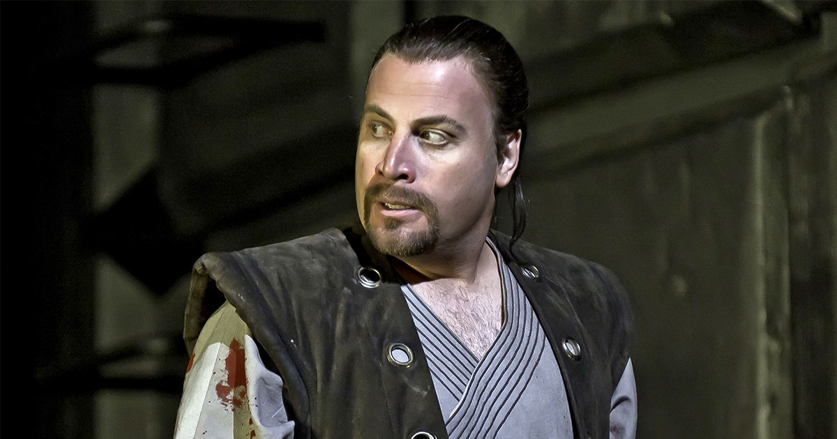 man with long brown hair and beard looking to the left