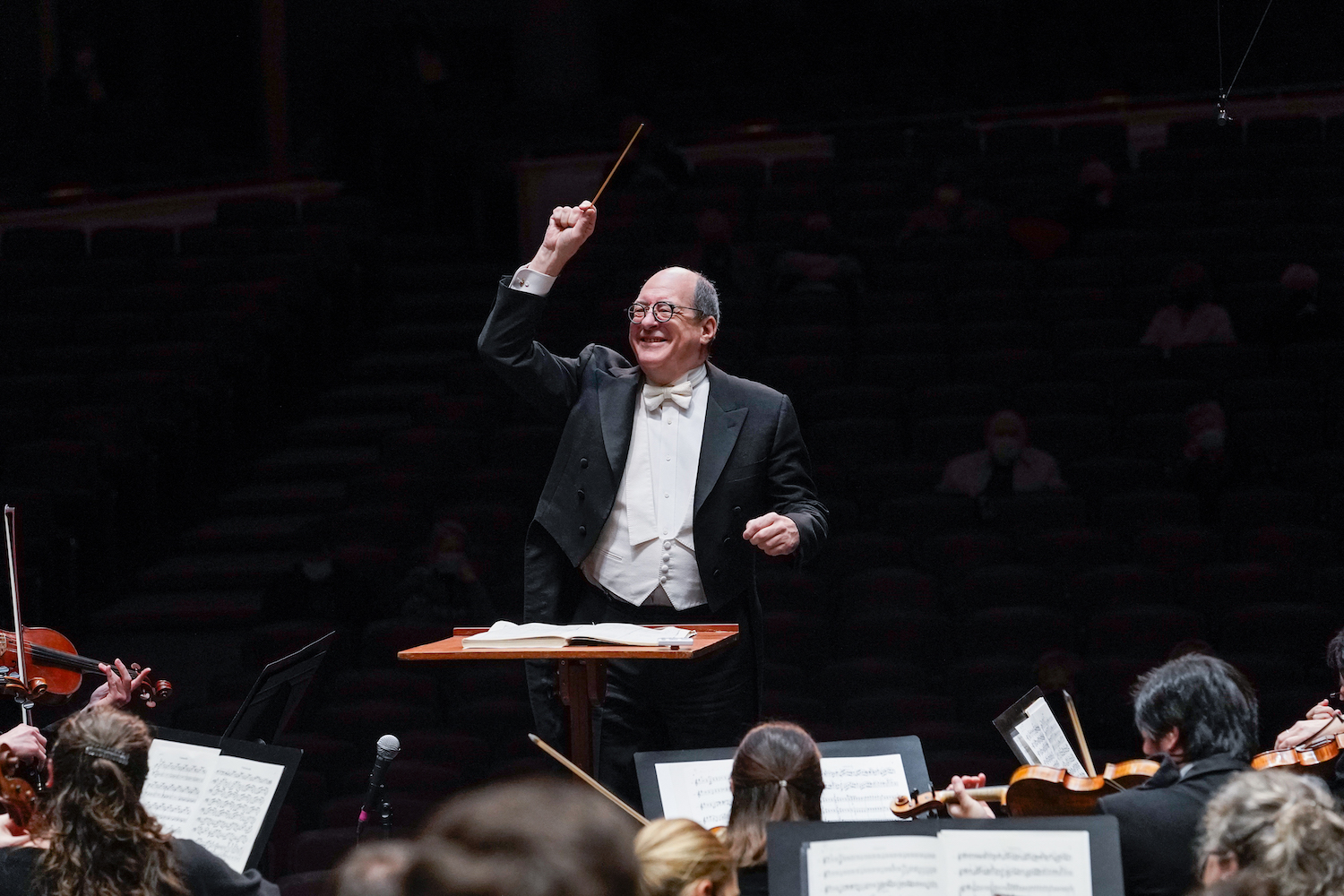 Conductor smiling with one arm raised conducting