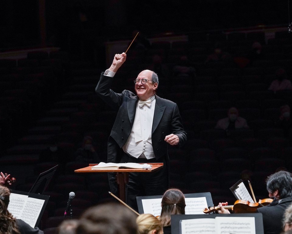 Conductor smiling with one arm raised conducting