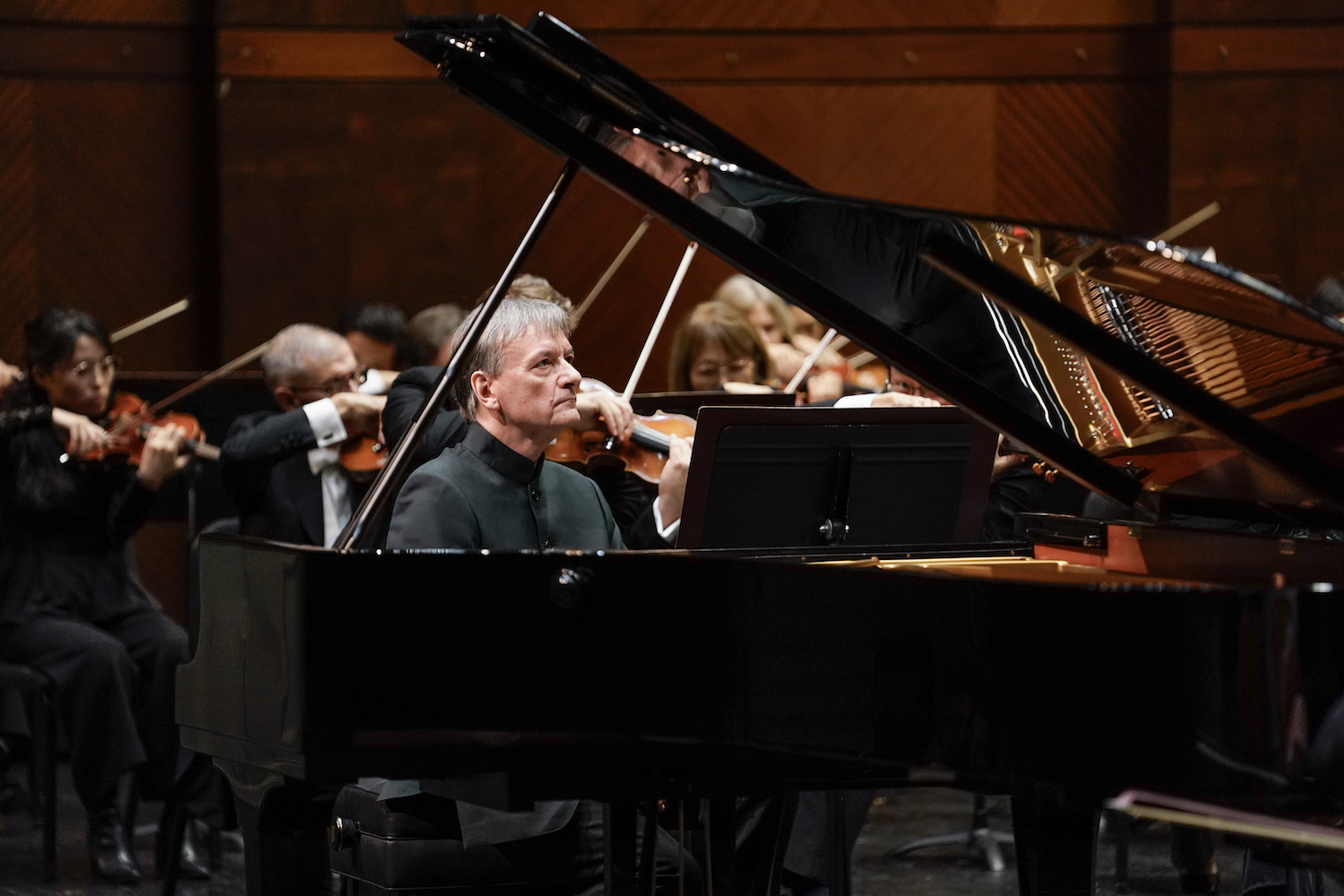 Man with grey hair and black shirt performing a grand piano