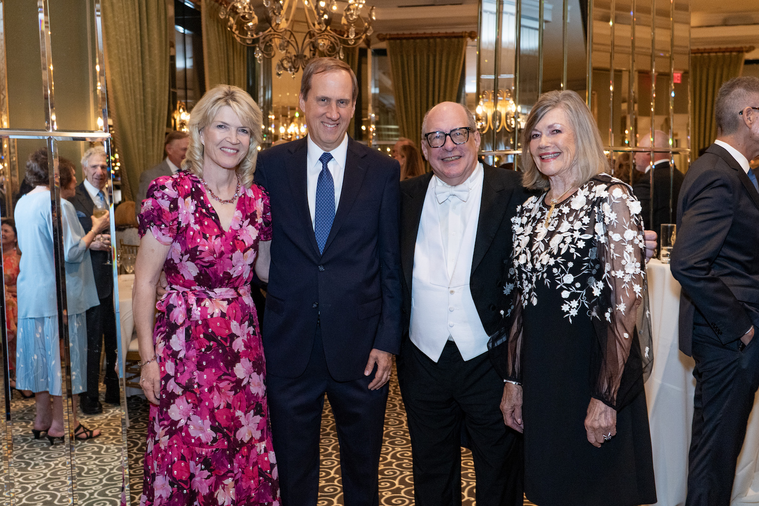 Four people smiling in cocktail attire in ballroom