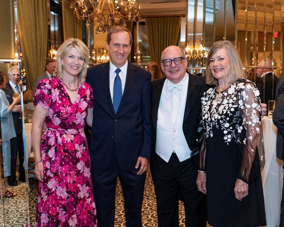 Four people smiling in cocktail attire in ballroom