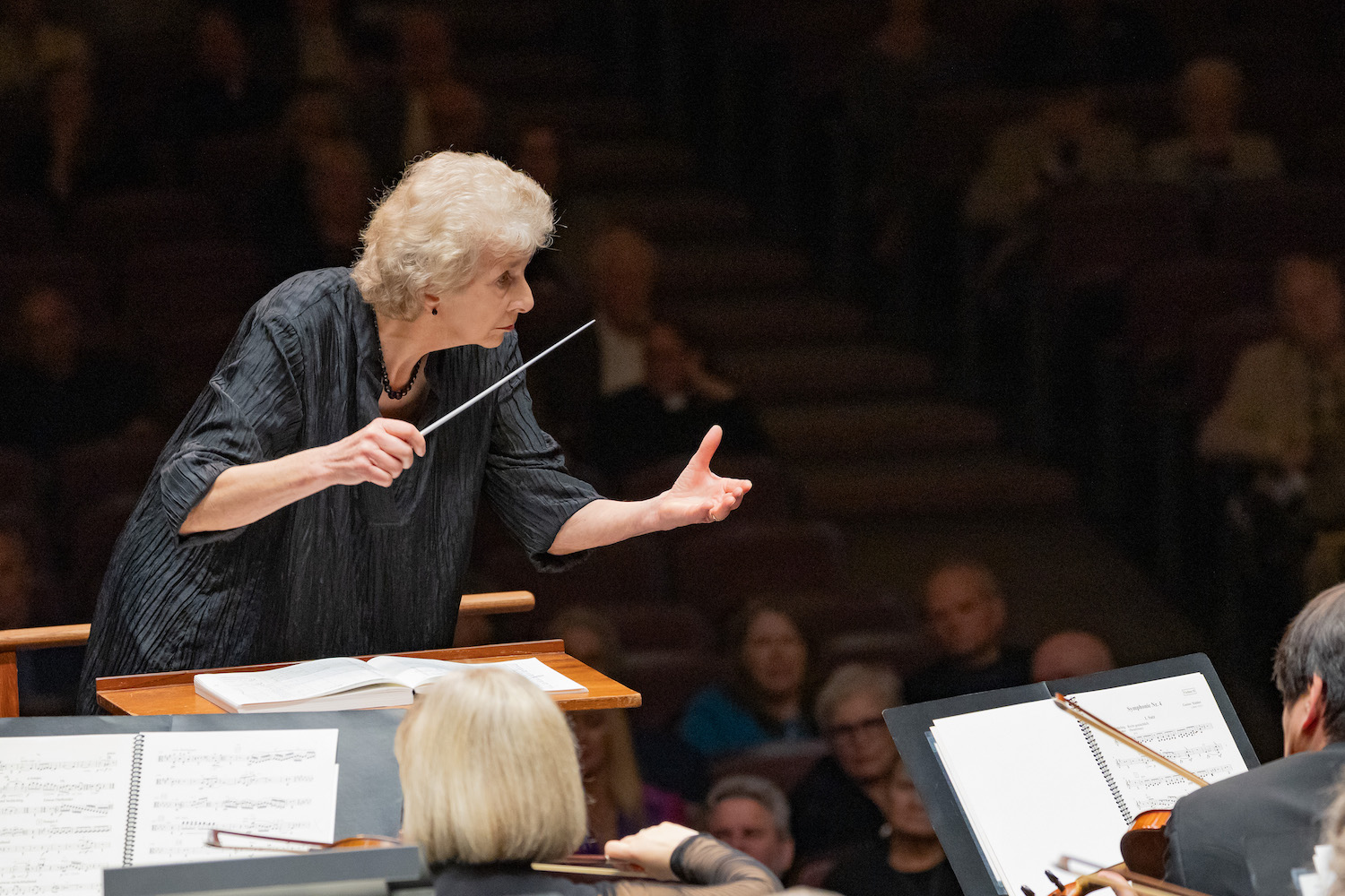 Woman turned to the side conducting an orchestra with her arms up